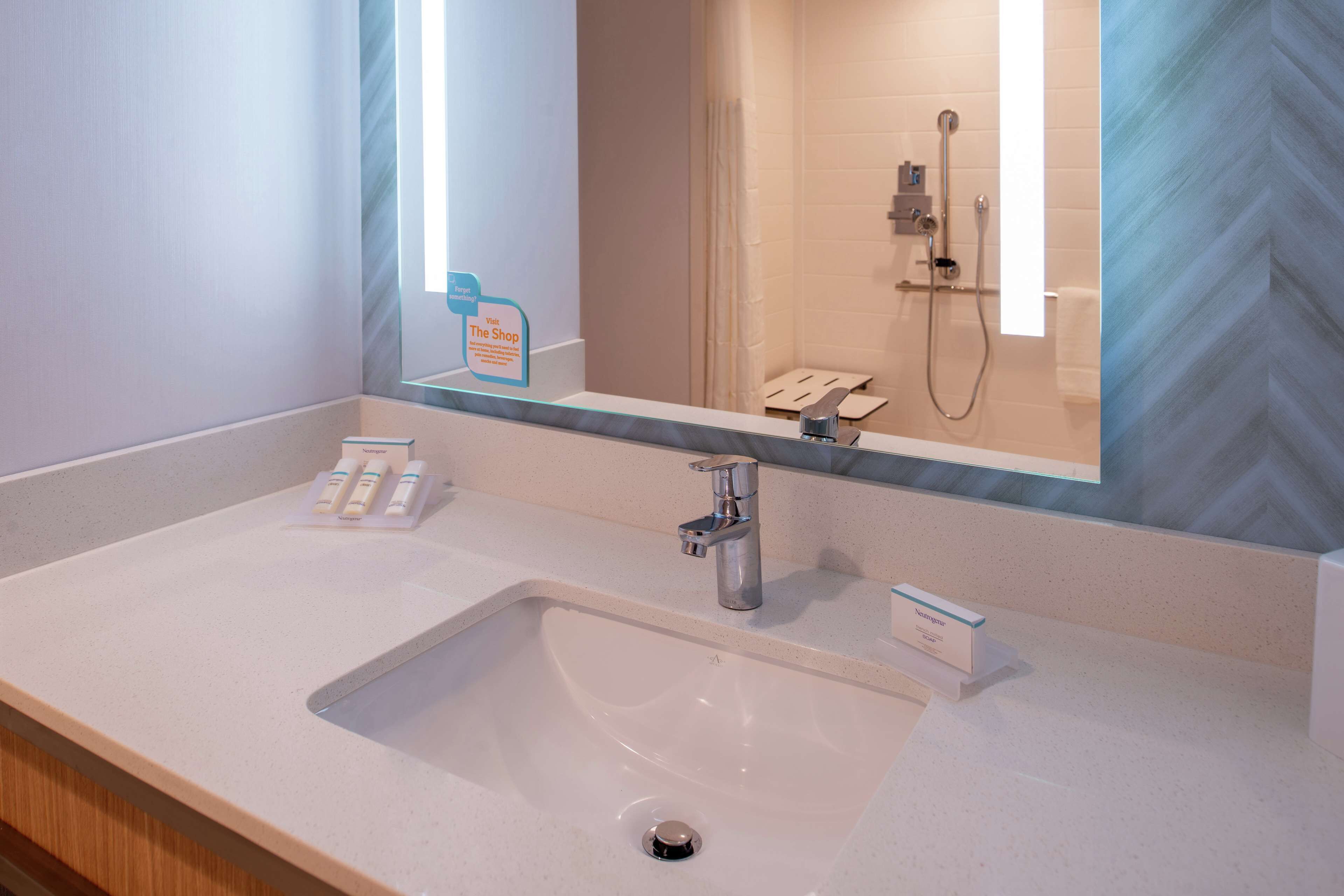 A modern bathroom with a large mirror, a sink, and a shower.