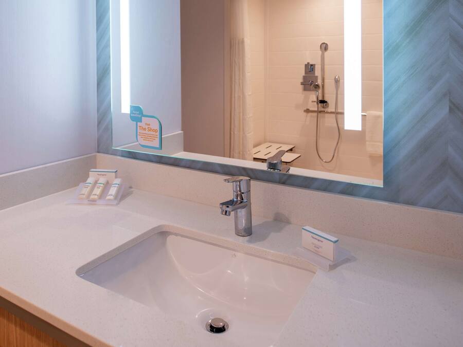 A modern bathroom with a large mirror, a sink, and a shower.