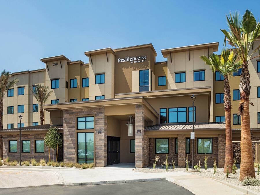A multi-story hotel with a modern design, featuring a prominent entrance with a covered area and palm trees.