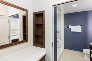 A modern bathroom with a large mirror, a shower, and a toilet.