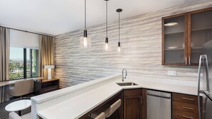 Une cuisine moderne avec un dosseret en marbre, un lave-vaisselle encastré et des luminaires suspendus.