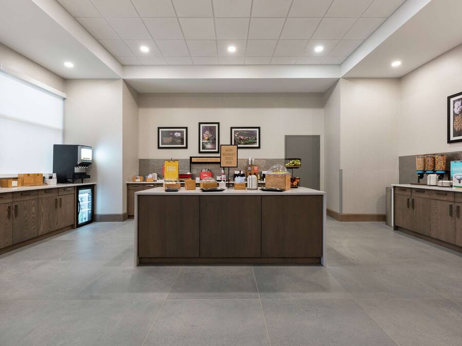 A modern kitchen area with a central island, equipped with various appliances and breakfast items.