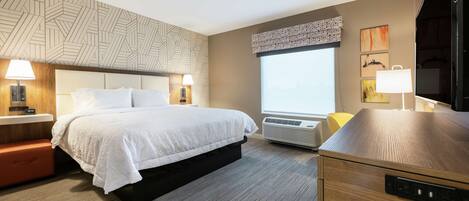 Una habitación de hotel moderna con una cama grande, lámparas de noche, calefacción integrada, un ventanal amplio y un televisor de pantalla plana.