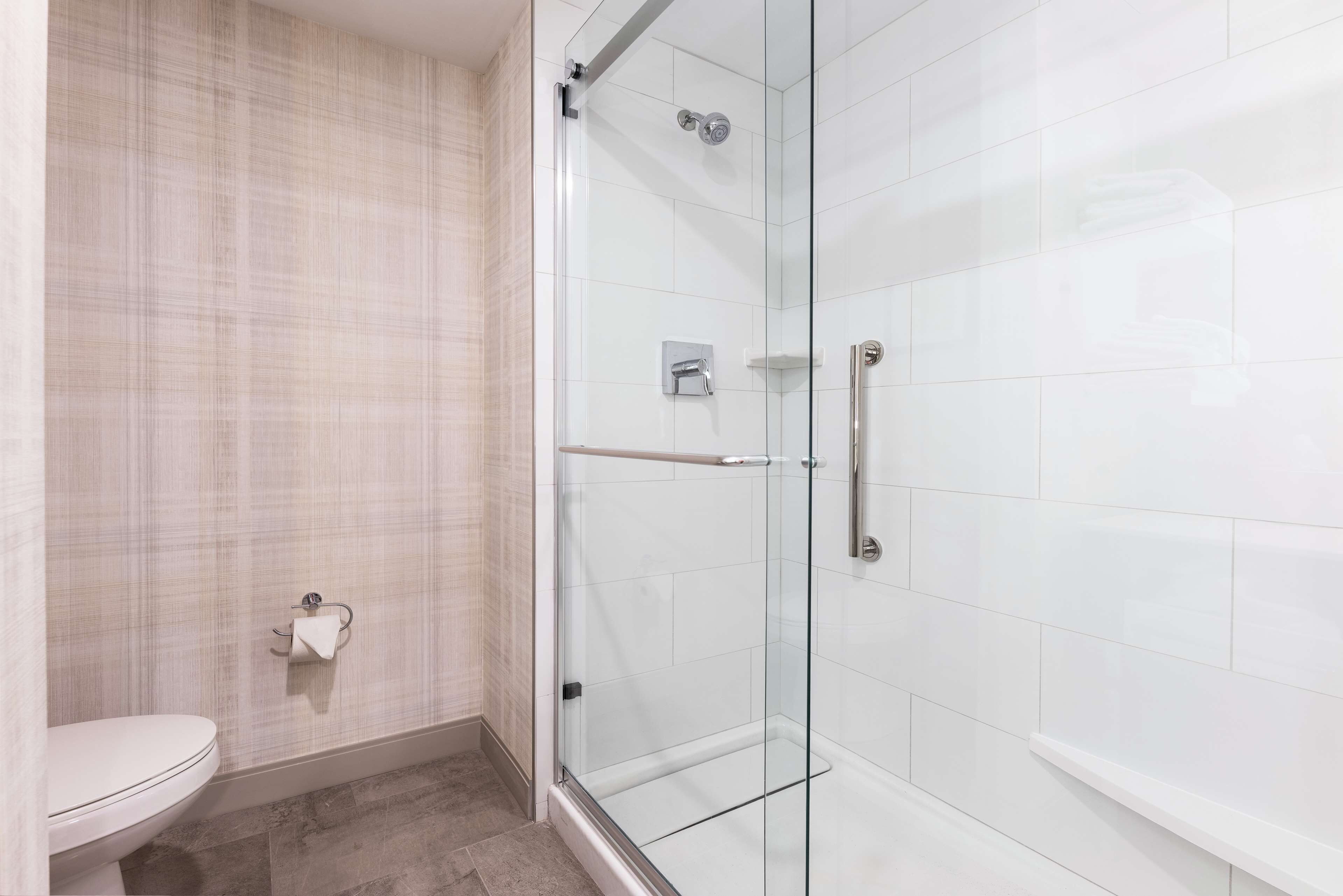 A modern bathroom with a glass shower enclosure, a toilet, and a towel rack.