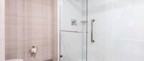 Une salle de bain moderne avec une douche à parois de verre, des toilettes et un porte-serviettes.