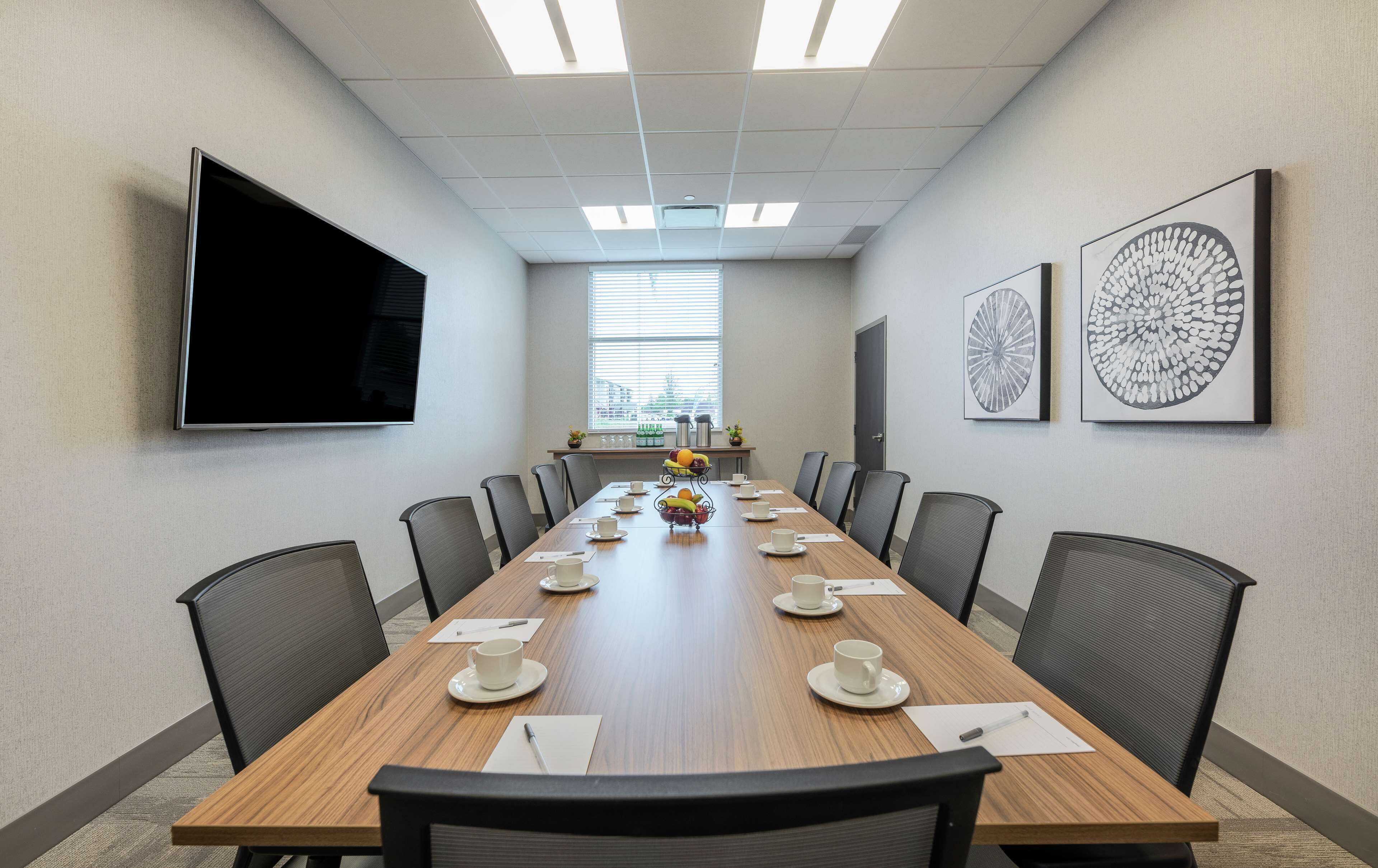 A conference room with a long table, chairs, a TV, and artwork on the walls.