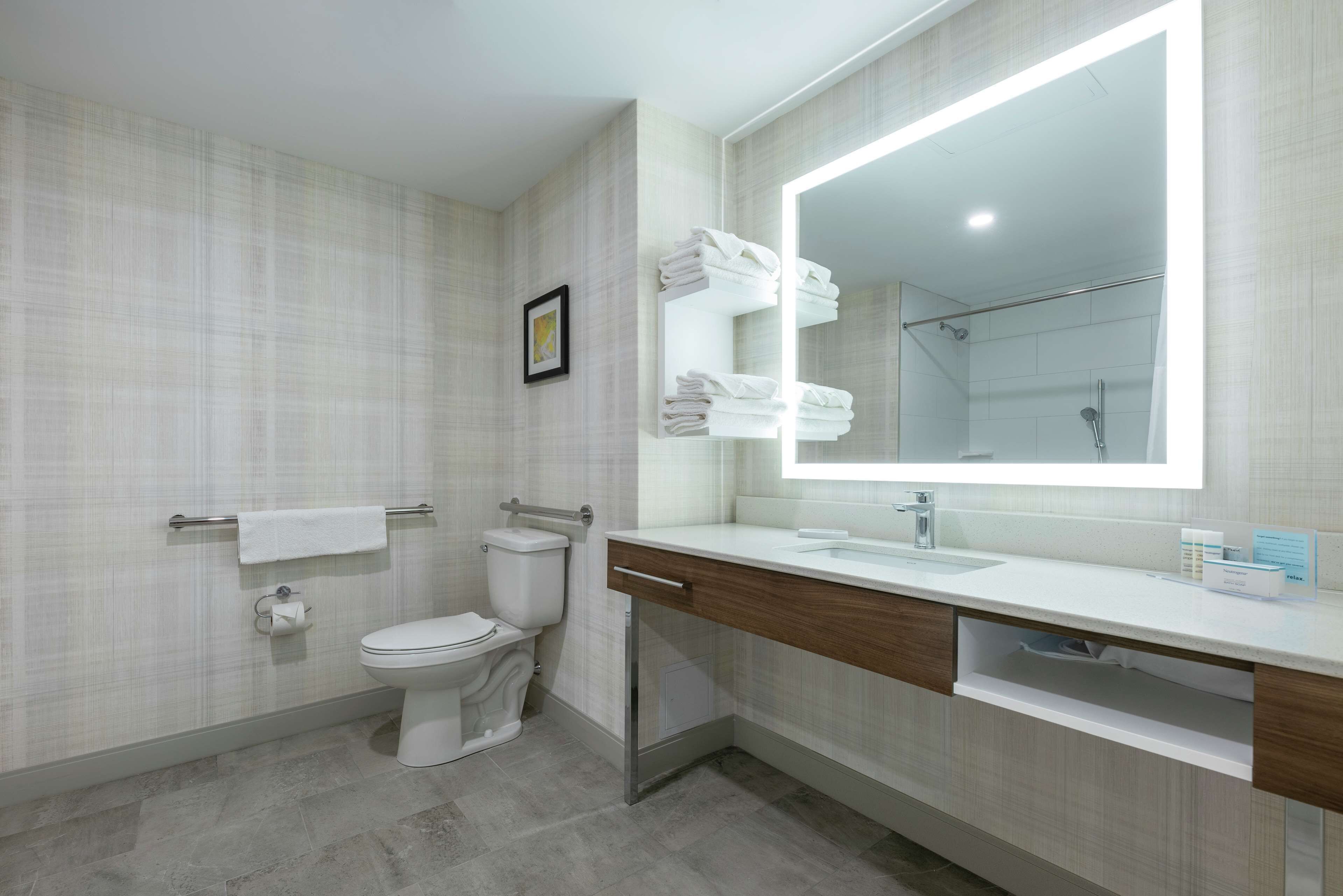 A modern bathroom with a toilet, sink, and large mirror.