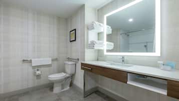 A modern bathroom with a toilet, sink, and large mirror.