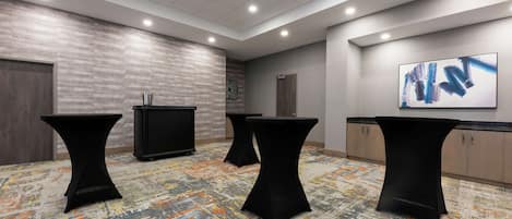 A conference room with three black tables, a clock on the wall, and a painting.