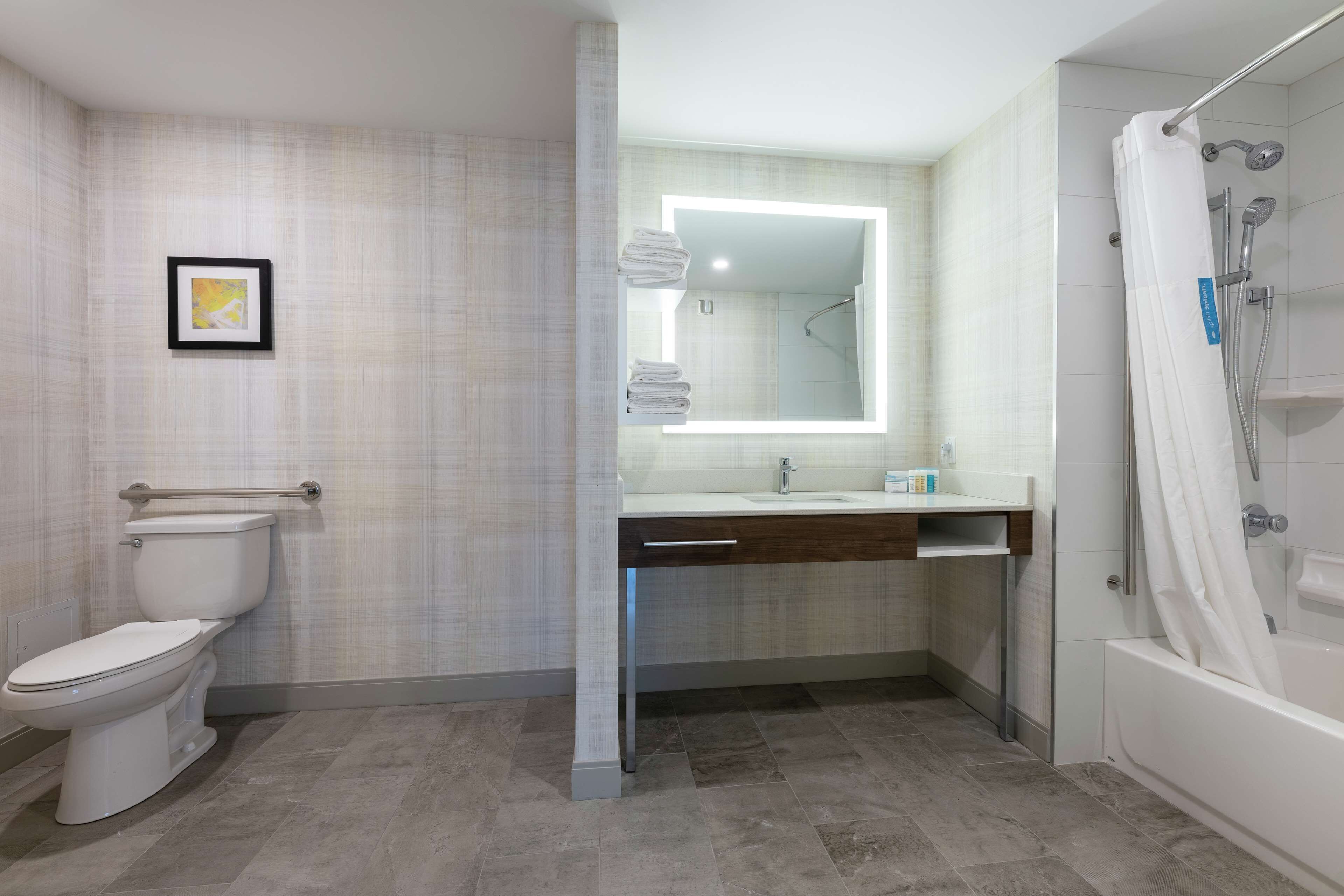 A modern bathroom with a toilet, sink, and shower.