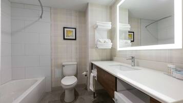 A modern bathroom with a bathtub, toilet, and vanity with a large mirror.