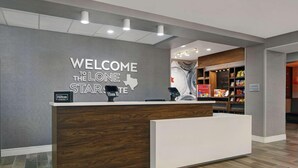 A hotel reception desk with a 'Welcome to the Lone Star' sign, a 'Hilton Honors' badge, and a 'Suite Shop' sign. - Hampton Inn Weslaco (Weslaco)