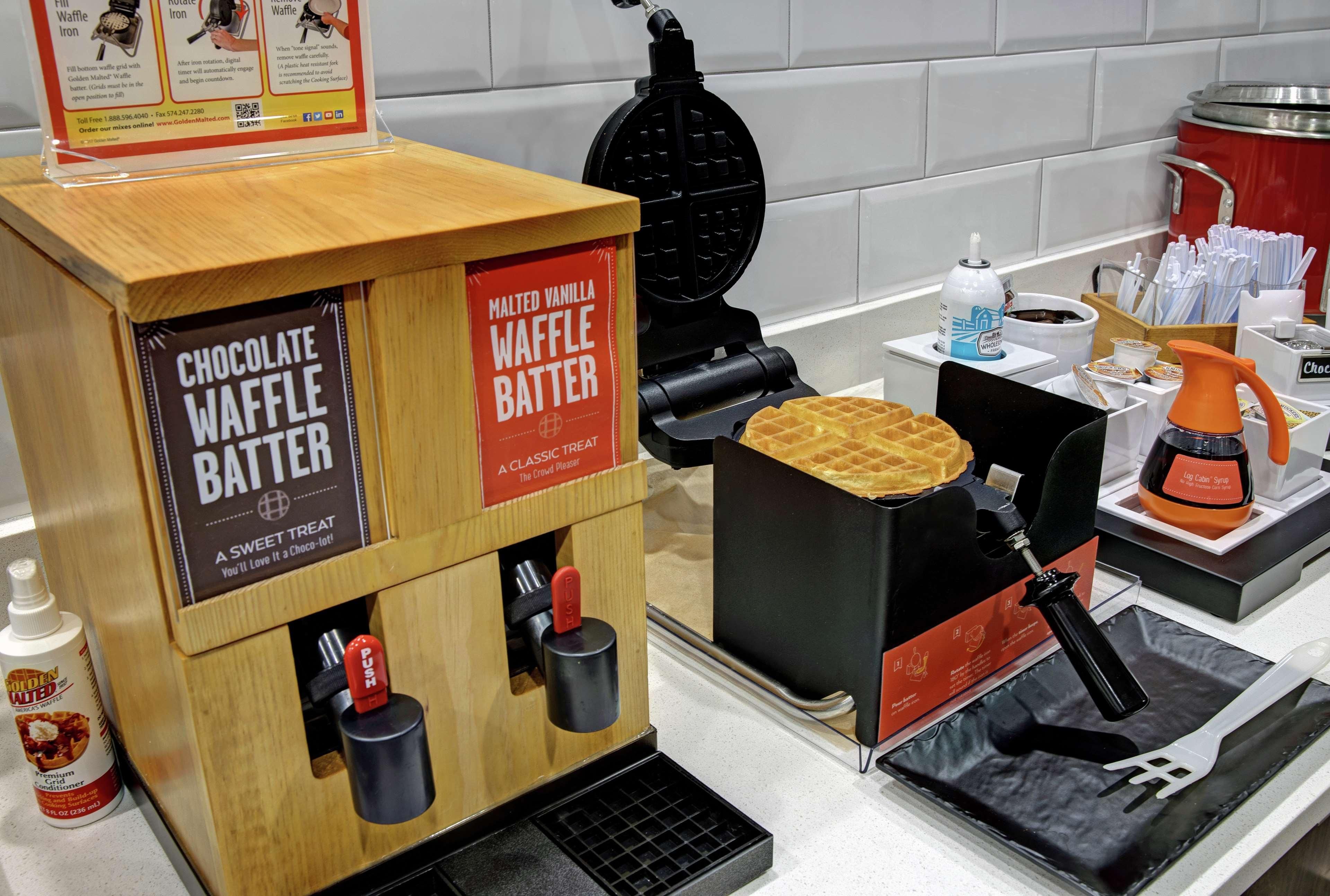 A waffle station with a waffle iron and batter dispensers.