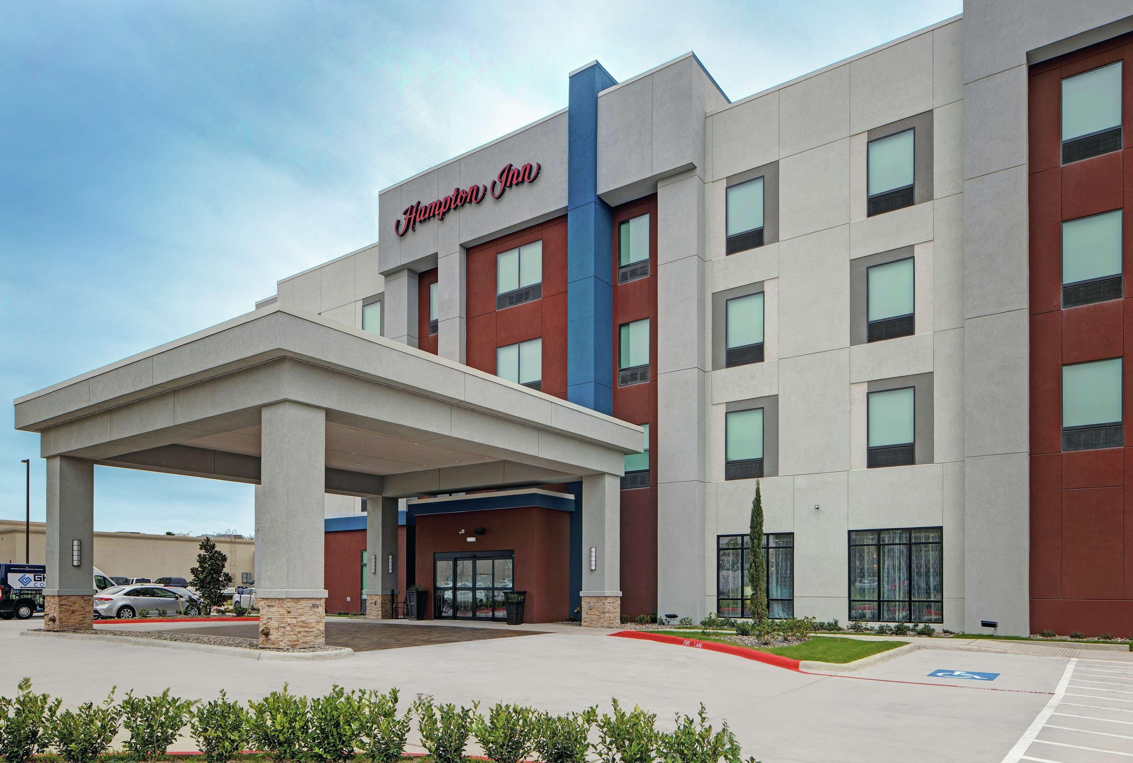 A Hampton Inn hotel with a covered entrance, multiple floors, and a parking lot.