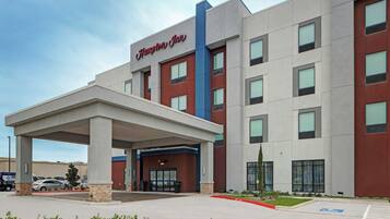 A Hampton Inn hotel with a covered entrance, multiple floors, and a parking lot.
