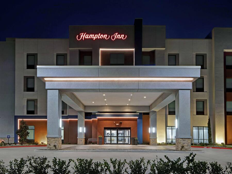 A Hampton Inn hotel with a modern facade, large entrance, and illuminated signage.