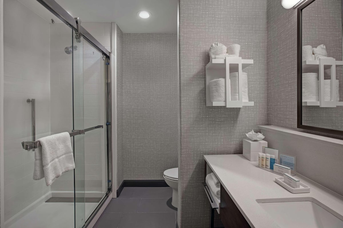 Une salle de bain moderne dotée d’une douche à parois de verre, de toilettes et d’un meuble-lavabo avec des articles de toilette.