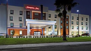 A modern hotel with a prominent neon sign, a covered entrance, and a well-maintained lawn. - Hampton Inn Weslaco (Weslaco)