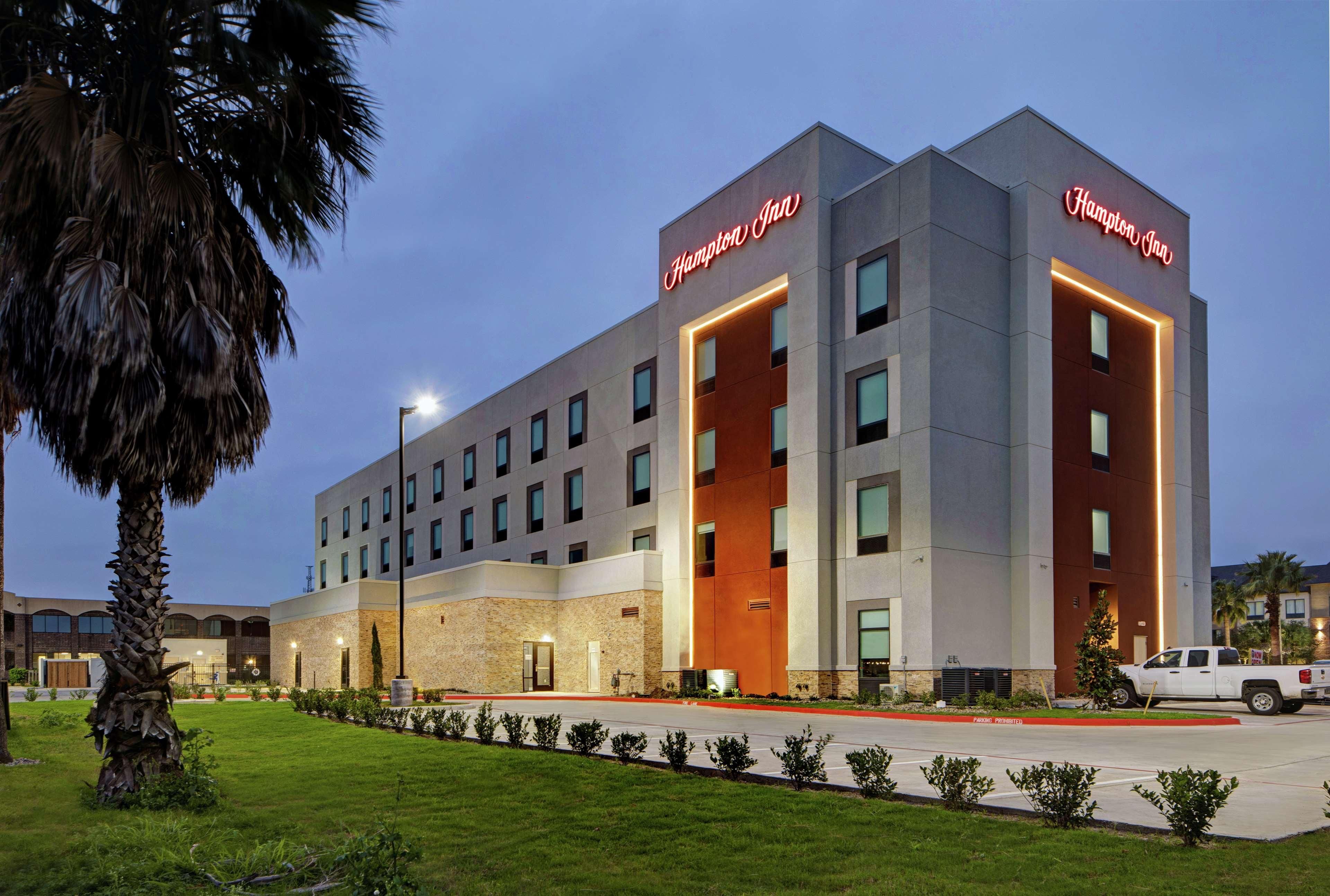 Ein modernes Hampton Inn Hotel mit auffälliger Beschilderung, einem gepflegten Rasen und einem Parkplatz.