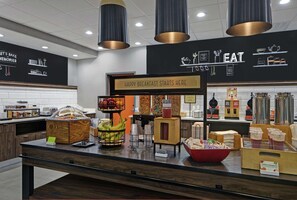 Zona de desayuno tipo buffet con un cartel que dice "HAPPY BREAKFAST STARTS HERE".
