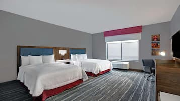 A hotel room with two beds, a desk, a chair, and a large window.