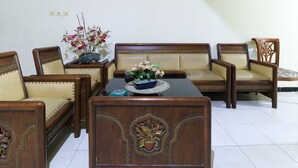 A room with a sofa set, a coffee table, and a floral arrangement. - Guest House Samarinda (Samarinda)