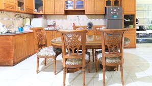 A kitchen with wooden cabinets, a dining table, and chairs. - Guest House Samarinda (Samarinda)