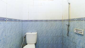 Un baño con inodoro, ducha y suelo de baldosas.