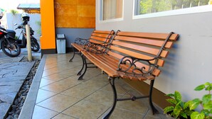 A bench with a metal frame and wooden slats, positioned on a tiled patio with a stone border. - Saidah Guest House (Bandung)