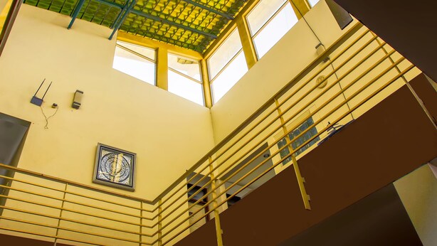 A high-ceilinged interior with a green-tiled roof, a central staircase, and a decorative wall piece. - Saidah Guest House (Bandung)