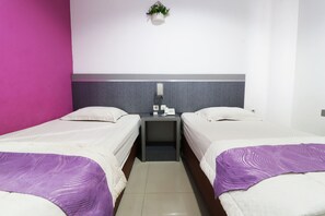 A hotel room with two single beds, a small bedside table with a phone and a lamp, and a wall-mounted plant. - Hasanah Guest House (Pekanbaru)