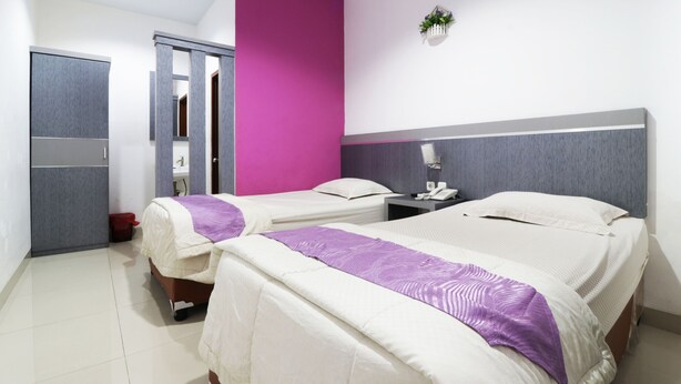 Une chambre d’hôtel avec deux lits, une salle de bain et une armoire.
