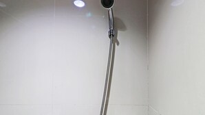 Un pommeau de douche fixé sur un mur carrelé.