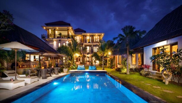 A large, modern house with a swimming pool, surrounded by lush greenery and palm trees. - Kandahill Bali (Pecatu)