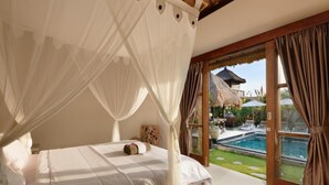 A bedroom with a four-poster bed, a view of a swimming pool, and a thatched-roof structure outside. - Kandahill Bali (Pecatu)