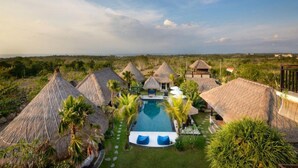 A resort with thatched-roof huts, a swimming pool, and a view of the savannah. - Kandahill Bali (Pecatu)