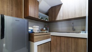 A modern kitchen with wooden cabinets, a stainless steel refrigerator, and a countertop with various appliances. - Oliver's Guest House (Pagedangan)
