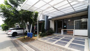 A modern building with a covered entrance, a white car parked outside, and a sign indicating it is a guest house. - Oliver's Guest House (Pagedangan)