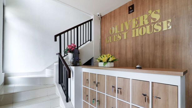 A reception area with a wooden wall and a sign that reads "OLIVER'S GUEST HOUSE." - Oliver's Guest House (Pagedangan)