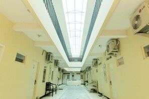 A corridor with a skylight, air conditioning units, and doors leading to rooms. - JJ House Gejayan (Depok)