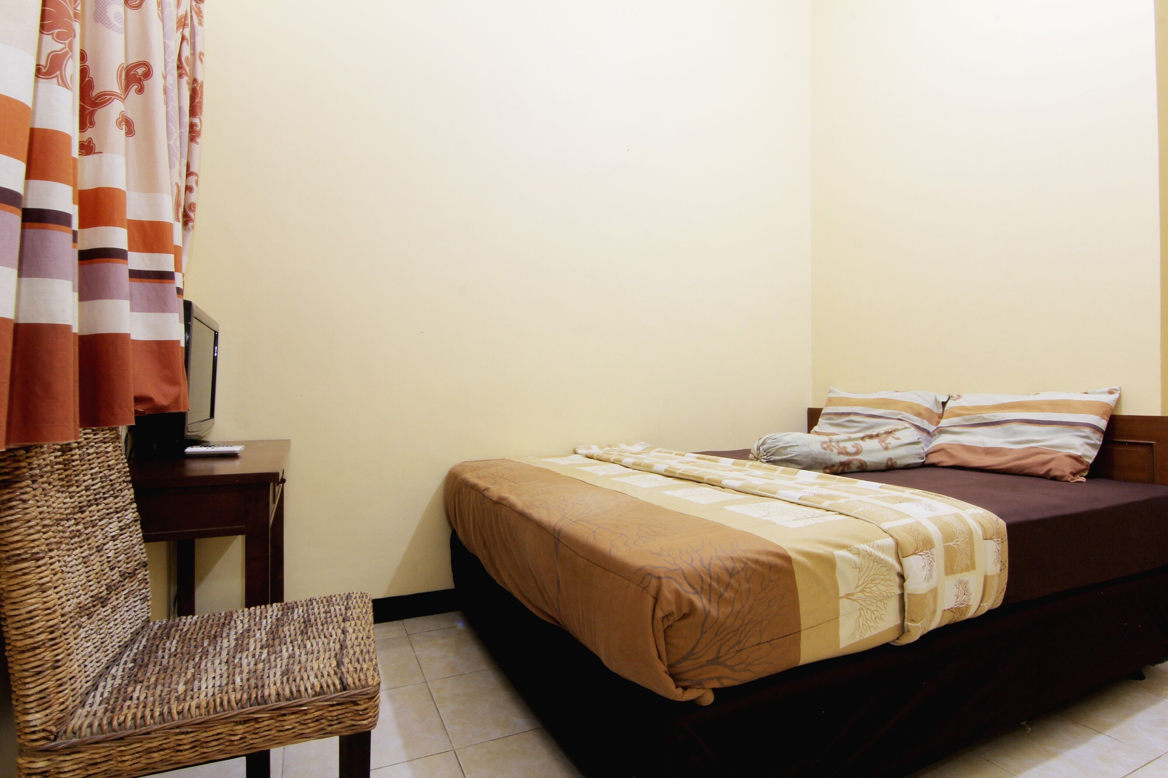 A bedroom with a bed, a chair, a desk, and a curtain.