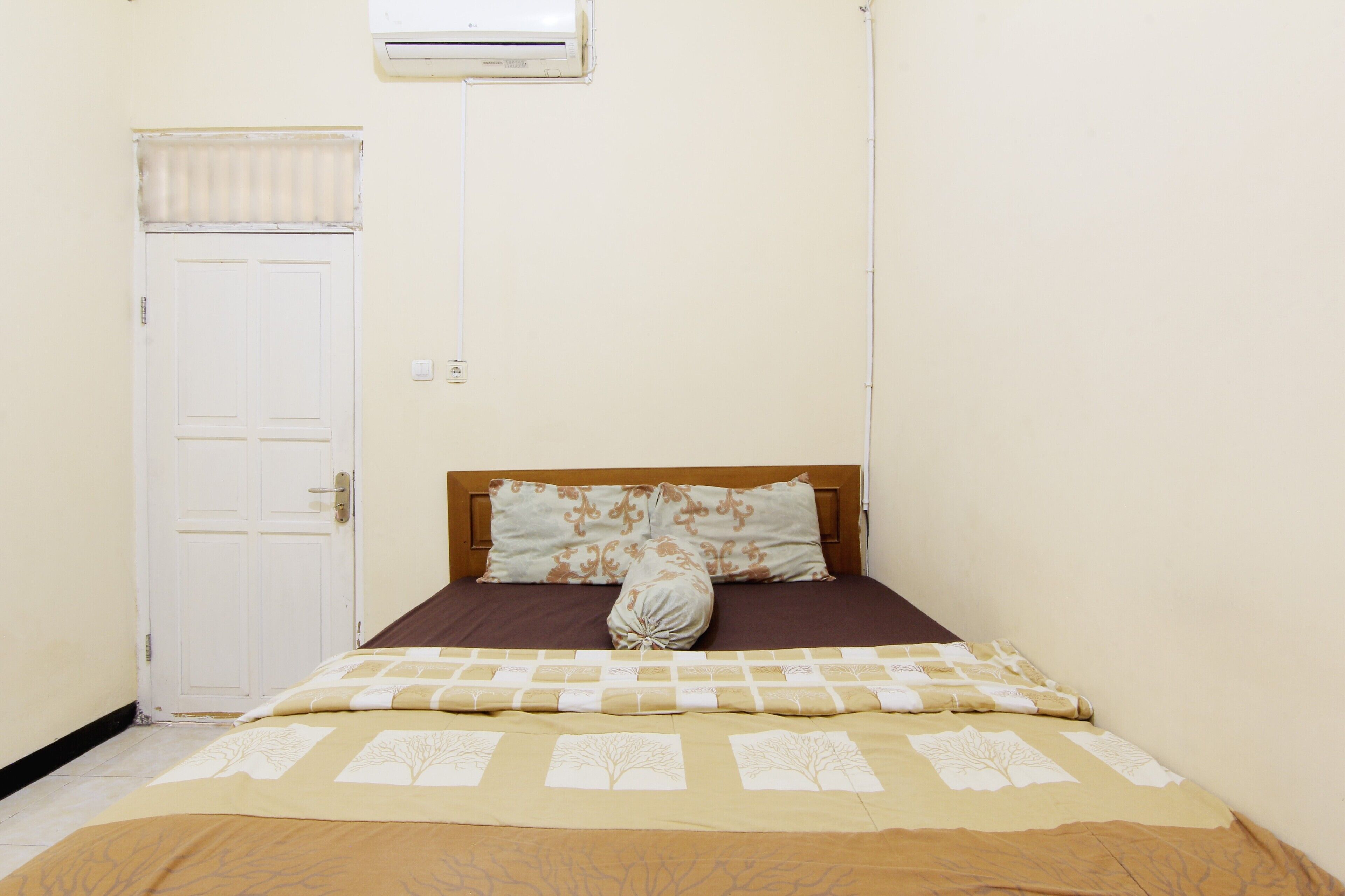 A bedroom with a bed, a door, and an air conditioning unit.