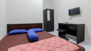 Un dormitorio con cama, escritorio, silla y televisión montada en la pared.