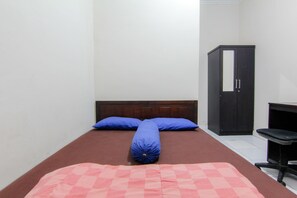 Ein Schlafzimmer mit Bett, zwei Kissen, einer karierten Decke, einem Kleiderschrank und einem Schreibtisch.