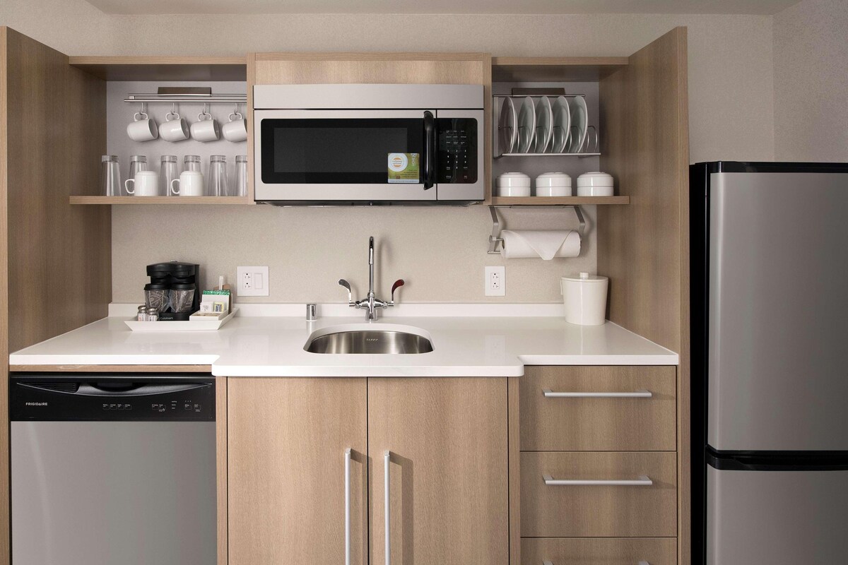Una cocina moderna con microondas integrado, pileta de acero inoxidable y lavavajillas.