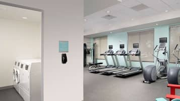 Ett gym med flera löpband, crosstrainers och en tvättmaskin med torktumlare.
