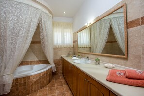 Une salle de bain équipée d’une baignoire, d’un lavabo, d’un miroir et d’un meuble-lavabo avec des serviettes.