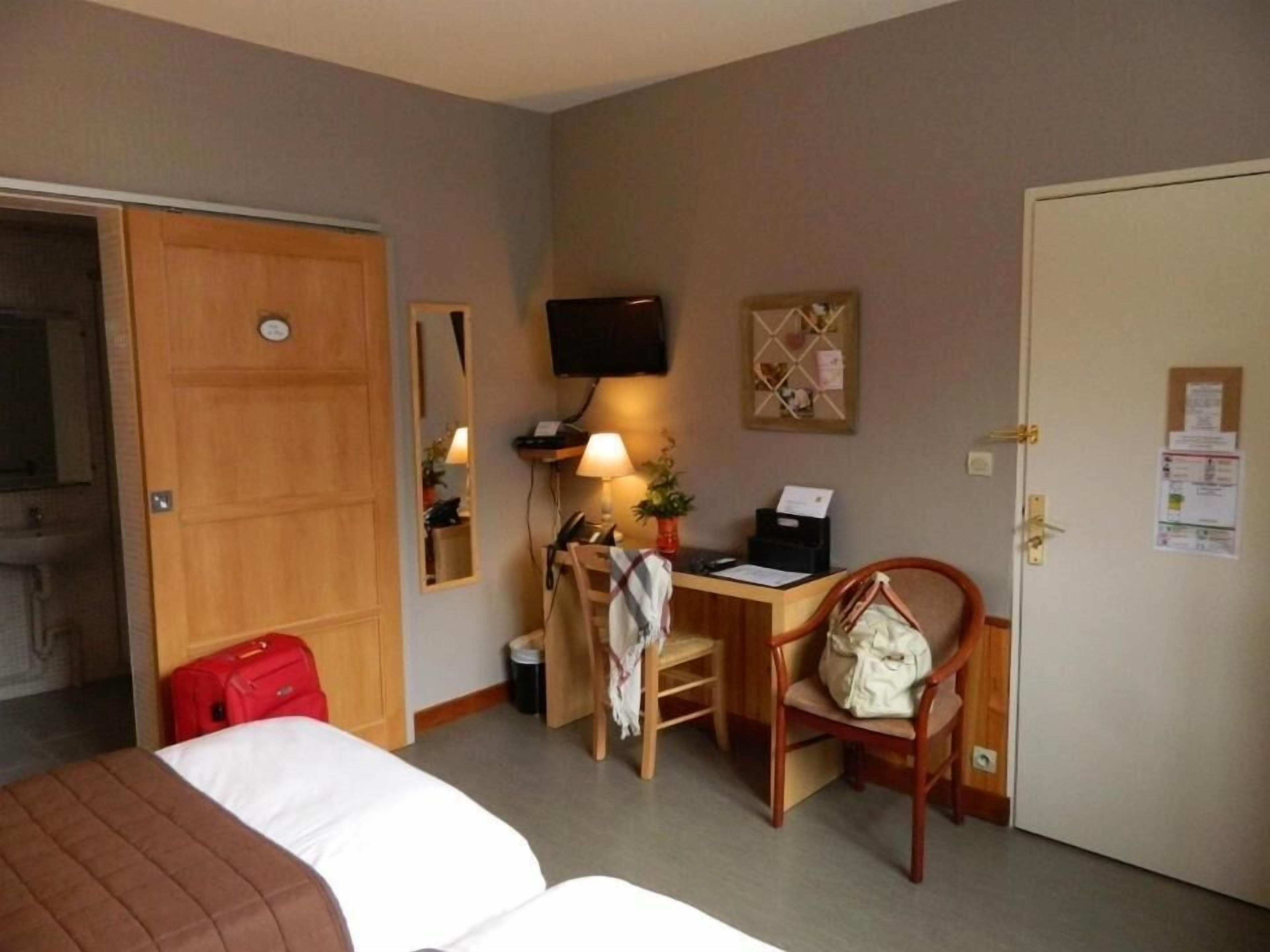 Een hotelkamer met een bed, een bureau met stoel, een televisie en een deur.