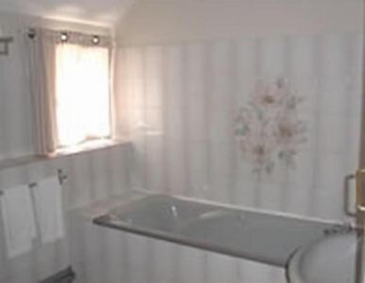 Une salle de bain avec une baignoire, une fenêtre avec des rideaux et un porte-serviettes.