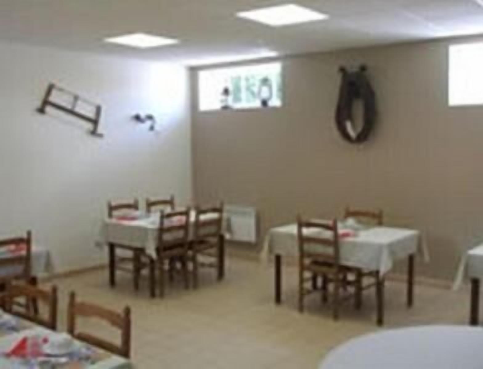 Una habitación con varias mesas y sillas, un reloj en la pared y una ventana con persianas.